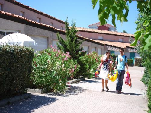 un homme et une femme marchant sur un trottoir dans l'établissement Airy Getaway by the Sea, à Saint Cyprien Plage