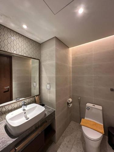 a bathroom with a sink and a toilet and a mirror at Apec Mandala Muine in Mui Ne