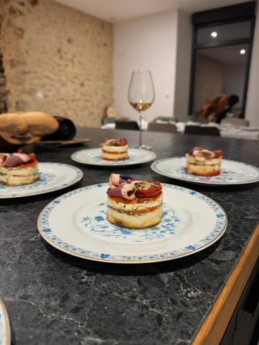 four plates of food on a counter with wine glasses at Domaine Le Petit Moulin in Lachy