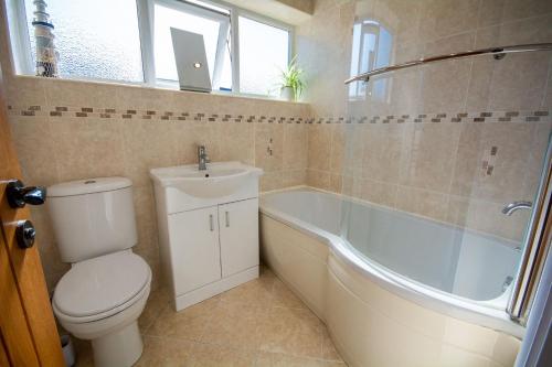 a bathroom with a toilet and a tub and a sink at 80 Breeze Hill in Benllech