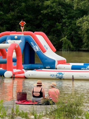 two people sitting in the water on a water slide at Chalets Camping Lacs d'Armagnac in Bretagne-dʼArmagnac