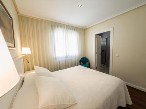a hotel room with a white bed and a window at Apartamentos Verdemar (VUT) in Llanes