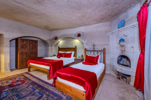 a bedroom with two beds and a fireplace at Onur Cave Cappadocia in Goreme