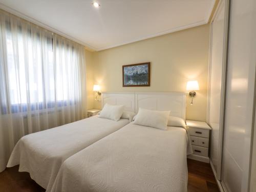 a bedroom with two beds with white sheets and a window at Apartamentos Verdemar (VUT) in Llanes