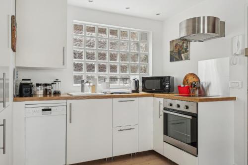 une cuisine blanche avec des armoires blanches et un micro-ondes dans l'établissement Nice apartment in the heart of Paris by Weekome, à Paris