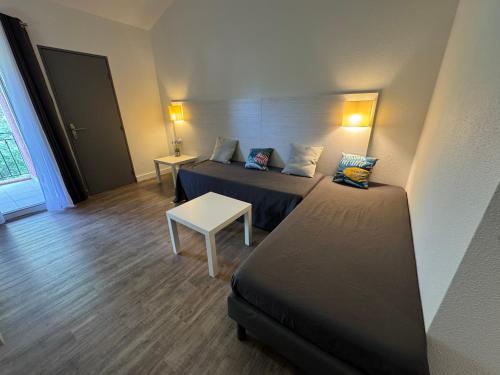 une chambre d'hôtel avec deux lits et une table dans l'établissement Studios aux hameaux de Camargue, à Arles