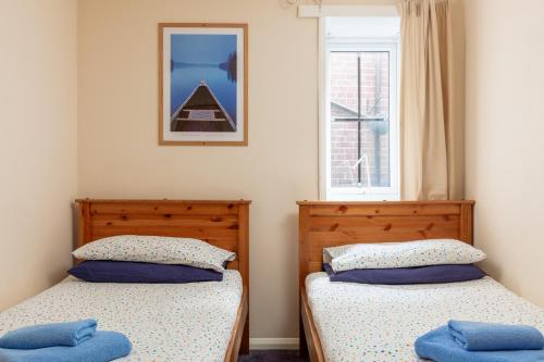 two twin beds in a room with a window at Discovery Accommodation in Whitby