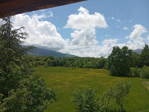 a field of grass with trees and mountains in the background at Famiglia nel vento in Caramanico Terme