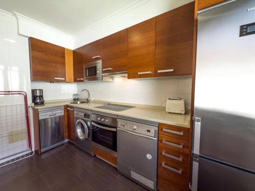 a kitchen with wooden cabinets and a washer and dryer at Apartamentos Verdemar (VUT) in Llanes
