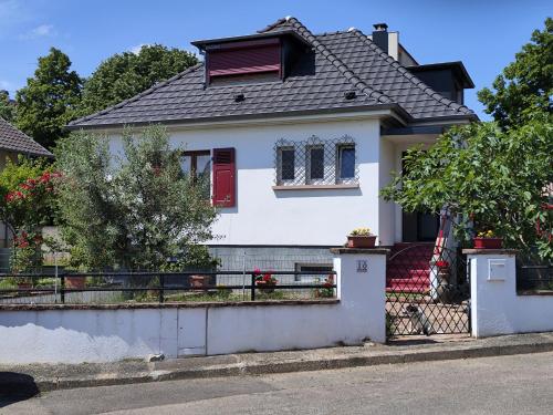 a white house with a red door and a fence at Colmar Room,chambre privée chez l'habitant,parking voiture devant la maison,garage moto et vélo in Colmar