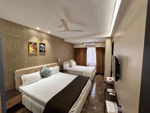 Una habitación de hotel con una cama y un televisor. en Hotel Mangal Shree, en Ujjain