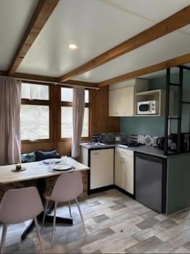 a kitchen with white cabinets and a table with chairs at Chalets Camping Lacs d'Armagnac in Bretagne-dʼArmagnac