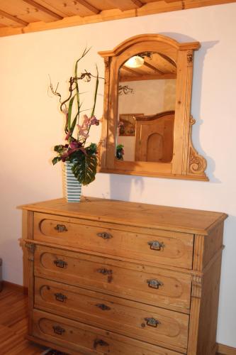 a dresser with a mirror and a vase with flowers on it at Bauernhof Kasleitner in Zell am Moos
