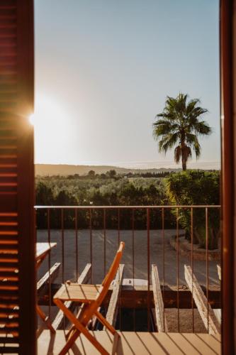 a balcony with chairs and a table and a palm tree at La Farm Baleares in Santa Maria del Camí