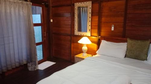 a bedroom with a bed with a lamp and a window at Medukuh Point Hill in Karangasem