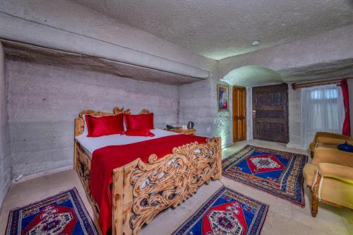 a bedroom with a bed with red pillows and red sheets at Onur Cave Cappadocia in Goreme