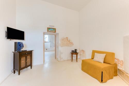 a living room with a chair and a tv at Masseria Scafazzi - Salento in Presicce