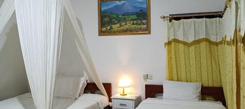 a bedroom with two beds and a picture on the wall at Moon view Bungalow's in Kelimutu