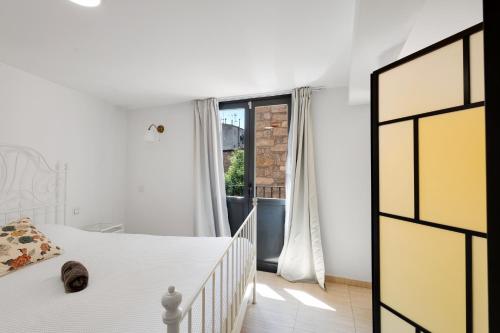 a white bedroom with a bed and a window at Wonderful loft centre Manresa in Manresa