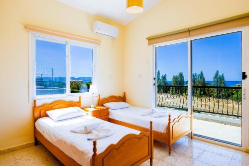 two beds in a room with a large window at Villa Aristotelis in Argaka