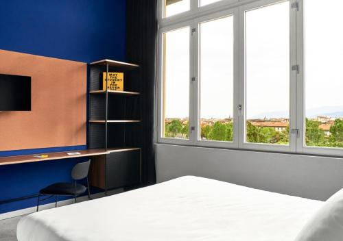 a bedroom with a bed and a desk and windows at The Social Hub Florence Lavagnini Extended Stay in Florence