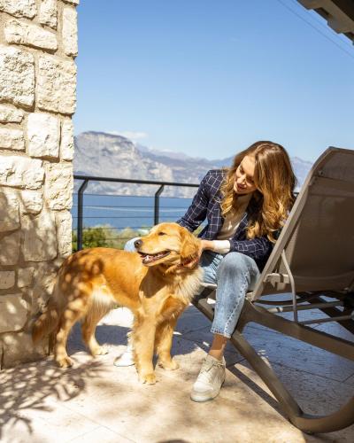 a woman sitting in a chair with a dog at Sunset Residence in Brenzone sul Garda