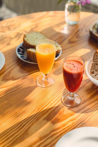 two glasses of orange juice and bread on a wooden table at Hotel A Miranda in Feás