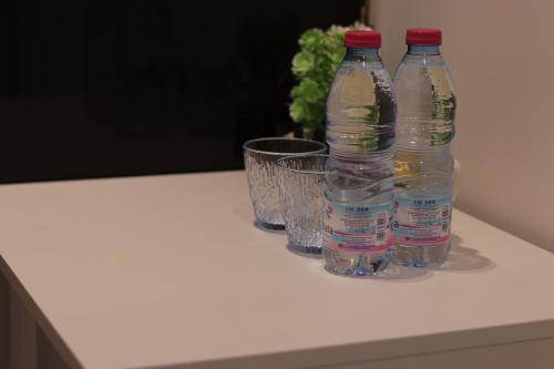 three bottles of water sitting on a counter with glasses at Klea Rooms in Himare
