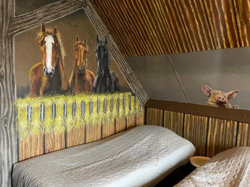 a bedroom with a painting of horses on the wall at Drouwenerzand Hotel in Drouwen