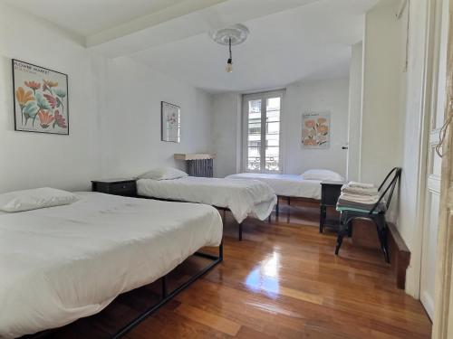 - une chambre avec 2 lits et une chaise dans l'établissement Le Jacquemart, à Romans-sur-Isère