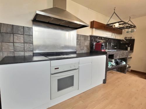 une cuisine avec des armoires blanches et un four à plaques de cuisson dans l'établissement Le Jacquemart, à Romans-sur-Isère