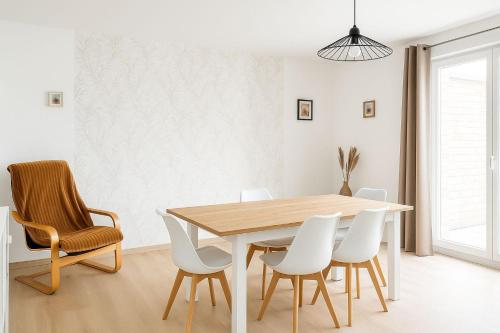 une salle à manger avec une table en bois et des chaises blanches dans l'établissement Chambre dans un appartement spacieux de 92m2, à Brest