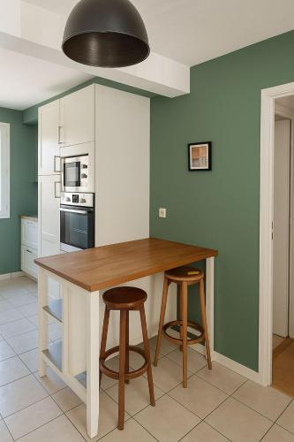 une cuisine avec une table en bois et deux tabourets dans l'établissement Chambre dans un appartement spacieux de 92m2, à Brest