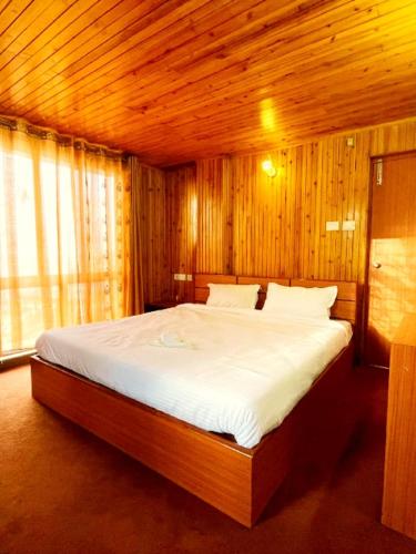 a bedroom with a large bed with wooden walls at Lake Kalibari Homes in Darjeeling