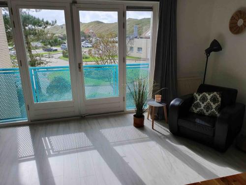 a living room with a chair and a view of a pool at Dünenblick am Meer aber 400 meter entfernt, mit renoviertem Badezimmer in Julianadorp