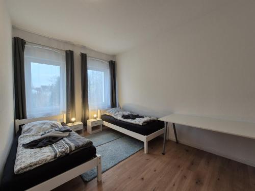 克里米乔Mikra Homes24 in Crimmitschau的客房设有两张床、一张书桌和两个窗户。