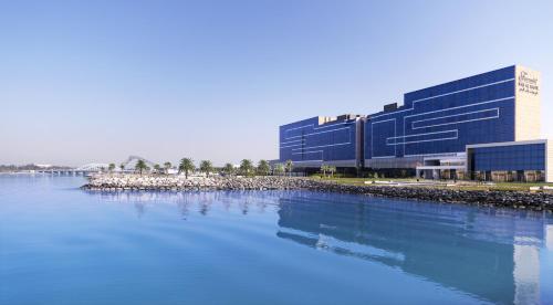 a large blue building next to a body of water at Fairmont Bab Al Bahr in Abu Dhabi