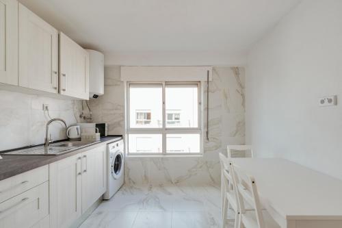 a white kitchen with a sink and a dishwasher at Bright & Family Flat in Paço de Arcos by HostWise in Lisbon