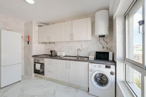 a kitchen with white cabinets and a washer and dryer at Bright & Family Flat in Paço de Arcos by HostWise in Lisbon
