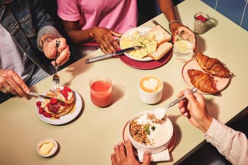 un grupo de personas sentadas alrededor de una mesa desayunando en The Social Hub Amsterdam West Extended Stay, en Ámsterdam