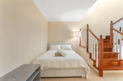a white bedroom with a bed and a staircase at Casa Valencia in Santa Cruz de Tenerife