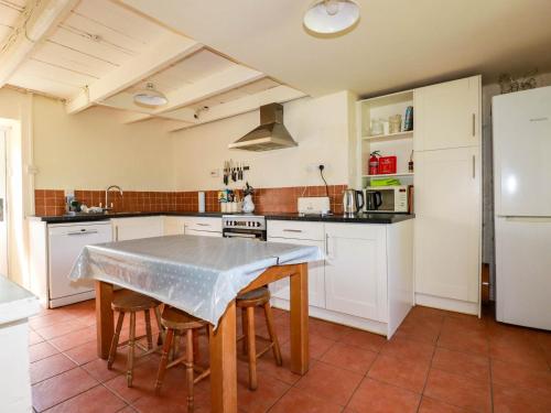 a kitchen with a table and chairs and a refrigerator at Polcreek Farmhouse in Veryan
