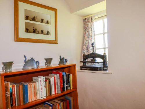 a book shelf filled with books next to a window at Polcreek Farmhouse in Veryan