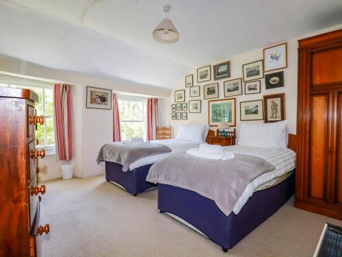 two beds in a bedroom with pictures on the wall at Polcreek Farmhouse in Veryan