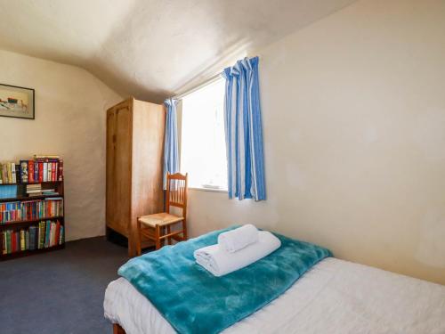 a bedroom with a bed and a window and a book shelf at Polcreek Farmhouse in Veryan