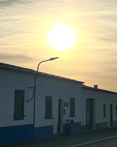 a street light in front of a building with the sun at Casa do Ocaso in Luz