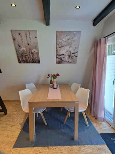 a dining room with a wooden table and white chairs at Ferienhaus Siebenschläfer mit privater Sauna in Bad Wünnenberg