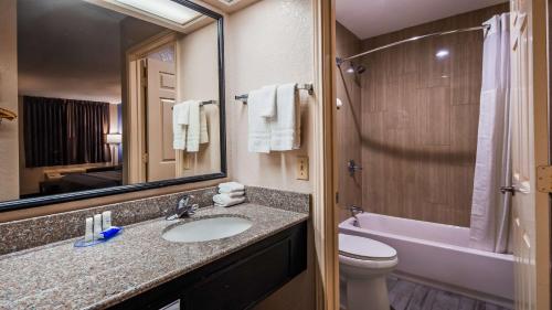 a bathroom with a sink and a toilet and a mirror at SureStay Hotel by Best Western Terrell in Terrell
