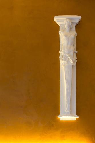 a white statue of a man on a yellow wall at Hotel Al Campanile - Luxury Suites & Apartments in Baveno