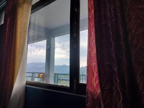 a window with a view of the ocean and mountains at Nirvana Heights Kasar Devi in Hawālbāgh